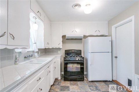 A kitchen with white cabinets and a black stove top oven.