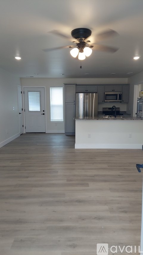 A kitchen with a fan and wooden floors.