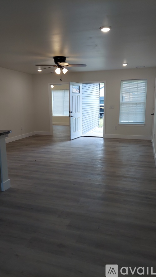 A spacious room with wooden flooring and a ceiling fan.