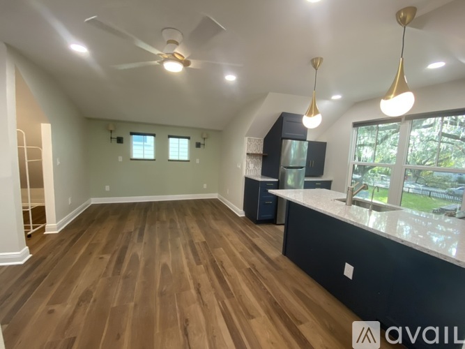 A spacious room with wood flooring and a ceiling fan.