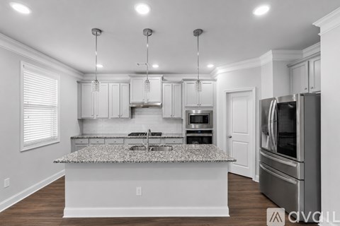 A modern kitchen with a granite countertop and stainless steel appliances.