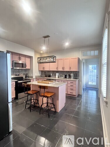 A kitchen with pink cabinets and a black refrigerator.