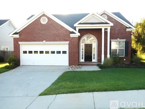 A red brick house with a white garage door and a large arched window.