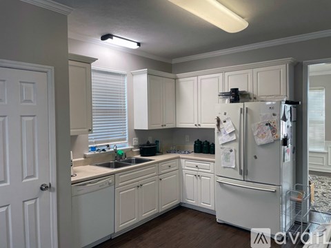 A kitchen with white cabinets and a white refrigerator.