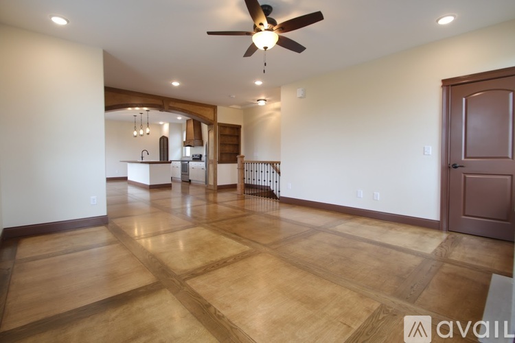 A spacious room with a ceiling fan and wooden flooring.