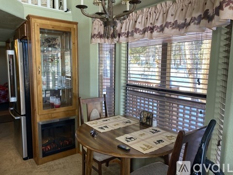 A dining room with a wooden table and chairs, a fireplace, and a chandelier.