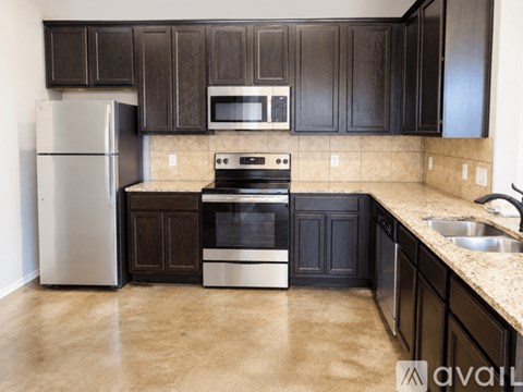 A kitchen with black cabinets and a stainless steel refrigerator.