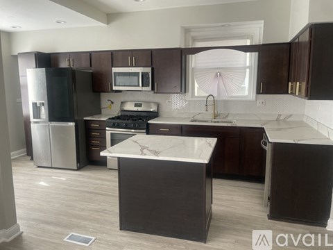 A kitchen with dark brown cabinets and a marble countertop.