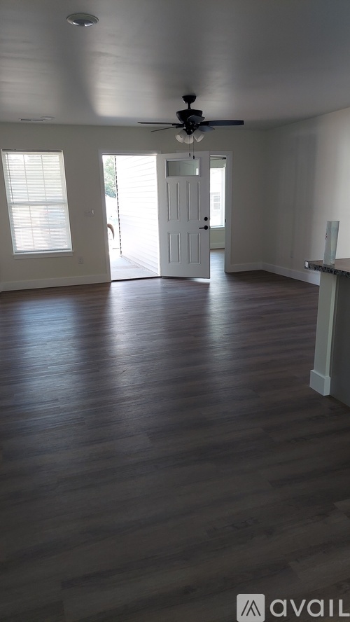 A room with a ceiling fan and wooden flooring.