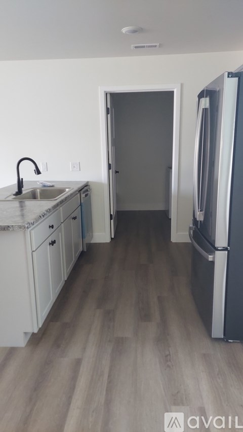 A kitchen with a sink, refrigerator, and cabinets.