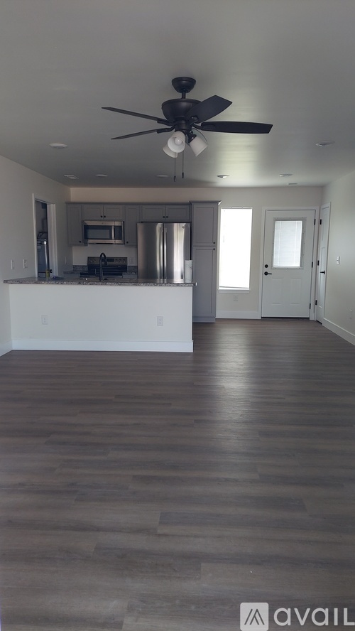 A spacious room with a ceiling fan and wooden flooring.