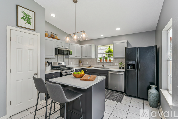 A modern kitchen with a large island and a black refrigerator.