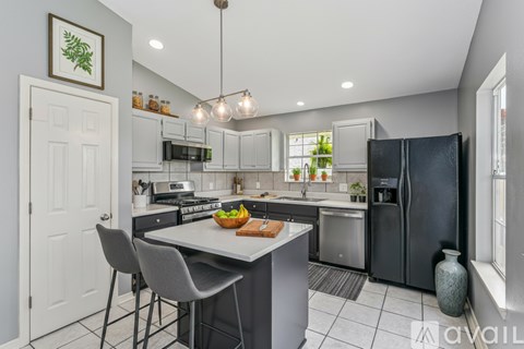 A modern kitchen with a large island and a black refrigerator.