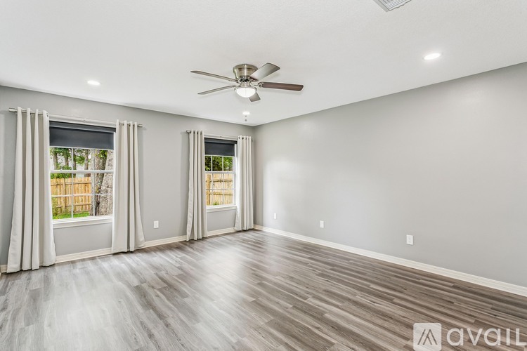 A spacious room with a ceiling fan and hardwood flooring.