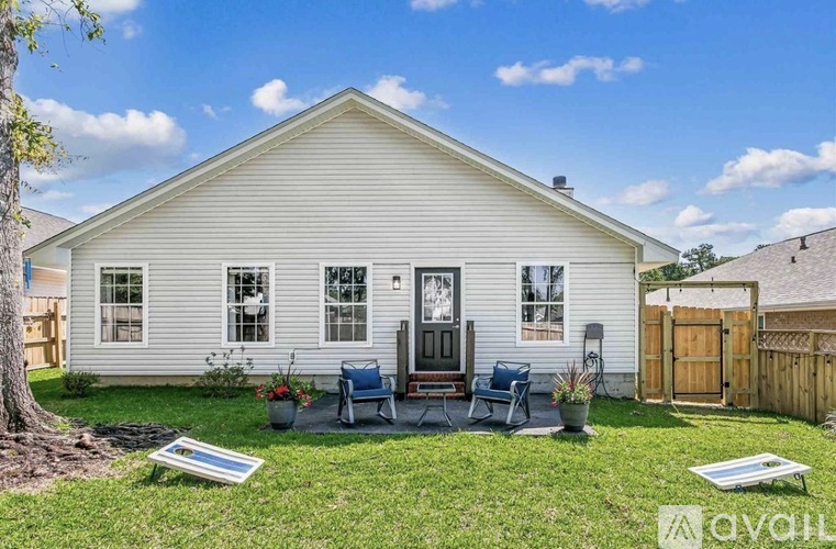 A house with a white exterior and a grey roof with a small front yard.