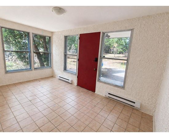 A room with a red door and tiled floor.