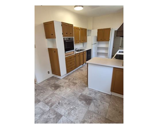 A kitchen with wooden cabinets and a tiled floor.
