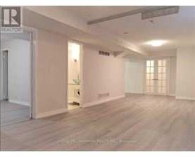 A spacious room with light wood flooring and white walls.
