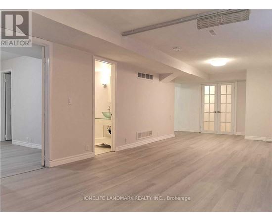 A spacious room with light wood flooring and white walls.