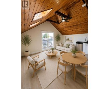 A living room with a wooden ceiling and a round table with chairs.
