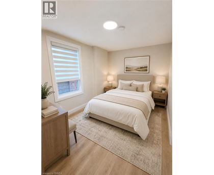 A bedroom with a large bed, a nightstand, and a window with blinds.