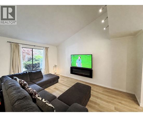 A living room with a large couch and a flat screen TV mounted on the wall.