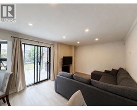 A living room with a grey couch and a fireplace.