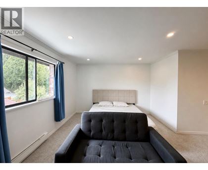 A bedroom with a large bed and a window with blue curtains.