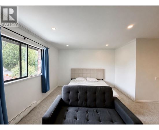 A bedroom with a large bed and a window with blue curtains.