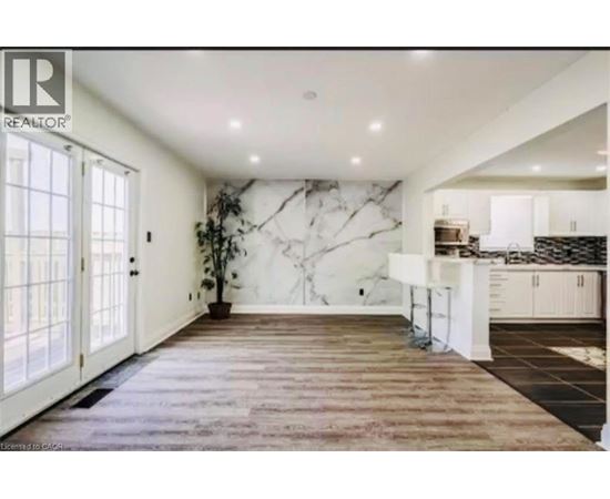 A spacious kitchen with a marble backsplash and wooden flooring.