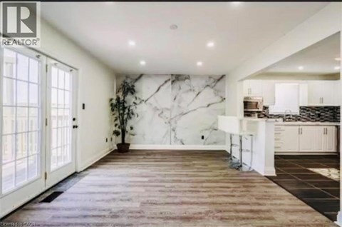 A spacious kitchen with a marble backsplash and wooden flooring.