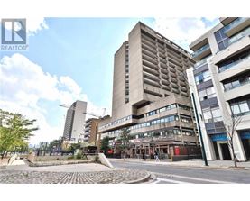 A tall building with a flat roof is in the middle of a street.