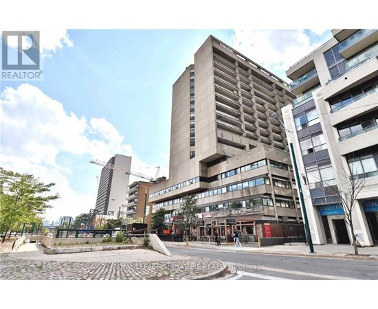 A tall building with a flat roof is in the middle of a street.