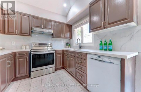 A kitchen with brown cabinets and a white dishwasher.