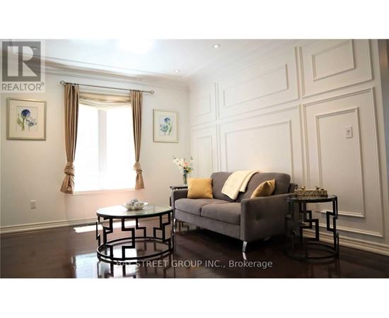 A living room with a grey couch, a glass table, and a painting on the wall.