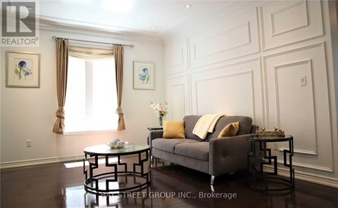 A living room with a grey couch, a glass table, and a painting on the wall.