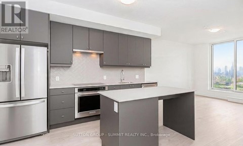A modern kitchen with a stainless steel refrigerator and a large island.