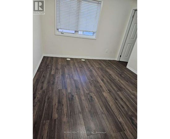 A room with wooden flooring and a window with blinds.