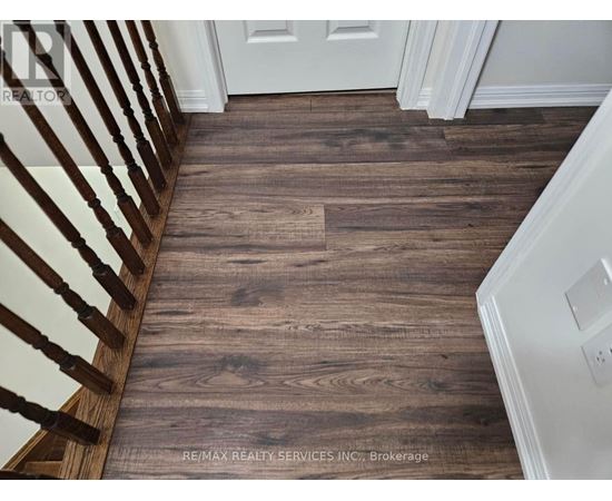 A wooden floor in a hallway with a white door.