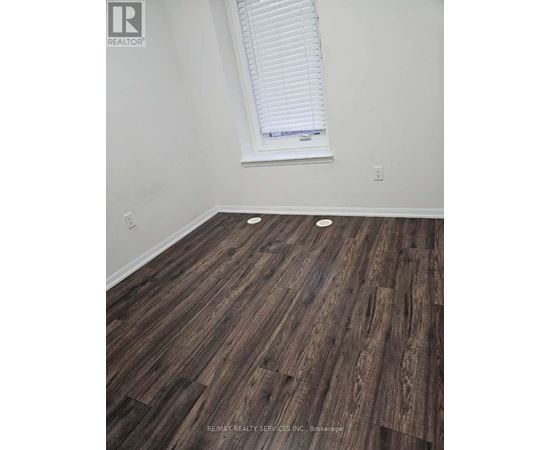 A room with a window and wooden flooring.