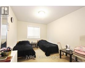 A bedroom with two beds and a table with a fan on it.