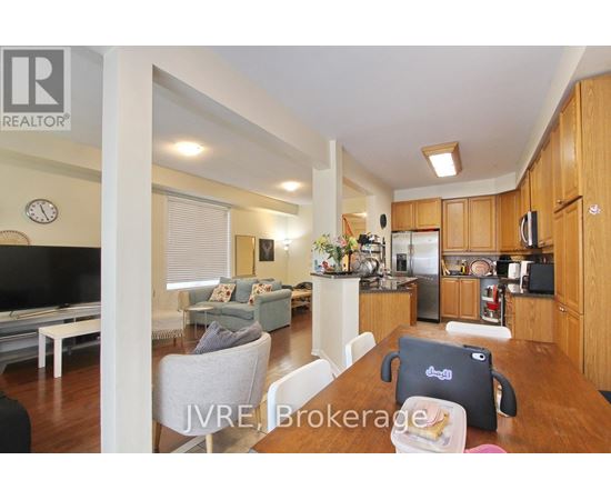 A well-lit kitchen and living room with wooden cabinets and a flat-screen TV.