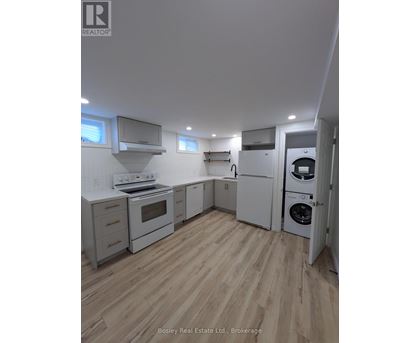 A kitchen with white appliances and wooden floors.