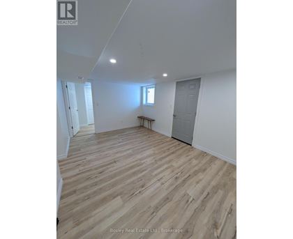 A room with wooden flooring and white walls, with a window and a door visible.