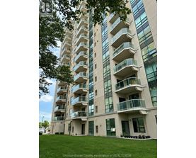 A tall building with balconies and windows is surrounded by greenery.