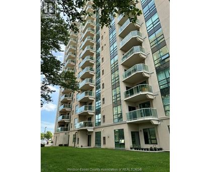 A tall building with balconies and windows is surrounded by greenery.