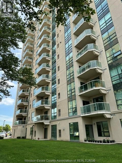 A tall building with balconies and windows is surrounded by greenery.