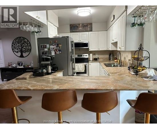 A kitchen with a marble countertop and brown barstools.