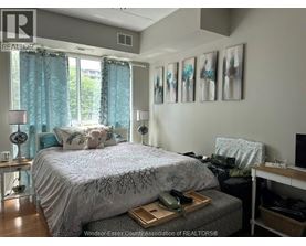 A bedroom with a bed, nightstand, and a window with curtains.