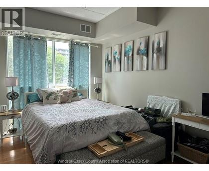 A bedroom with a bed, nightstand, and a window with curtains.